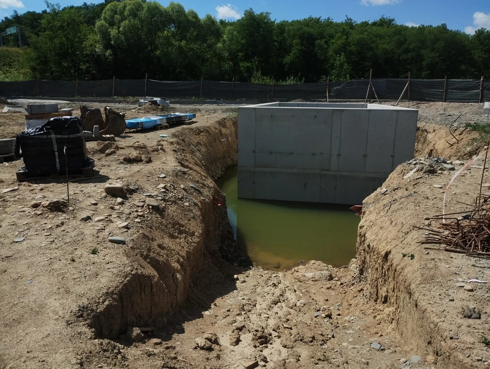 Wykop ziemny z betonową komorą fundamentową stojącą w wodzie prace ziemne
