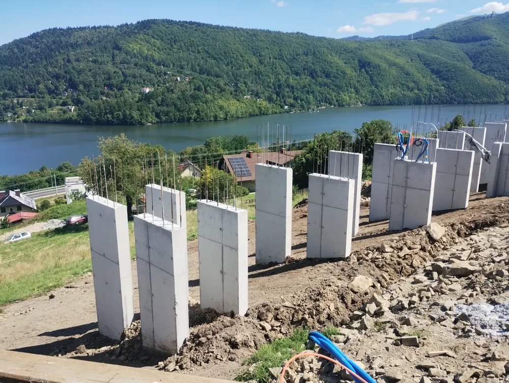 Roboty żelbetowe – betonowe ściany fundamentowe z wystającymi zbrojeniami na stoku nad jeziorem