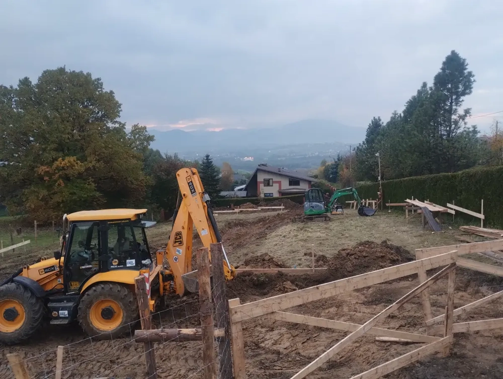Prace ziemne z koparką i ładowarką podczas wykopów pod fundamenty na terenie budowy