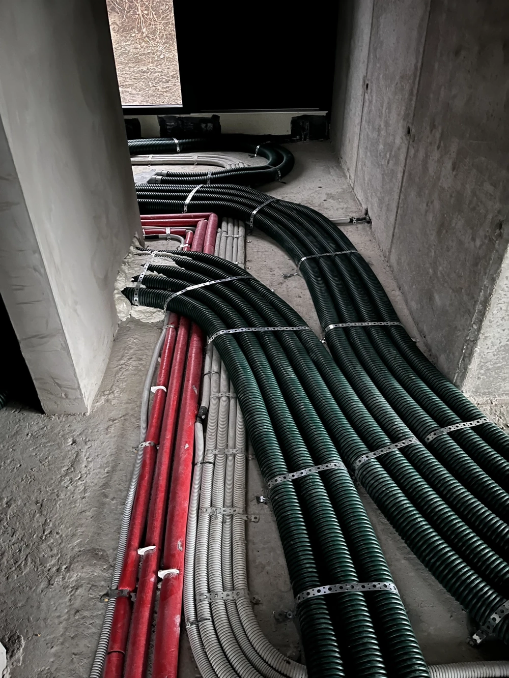 Ułożone plastikowe peszle kablowe prowadzące instalacje elektryczne na surowej posadzce betonowej