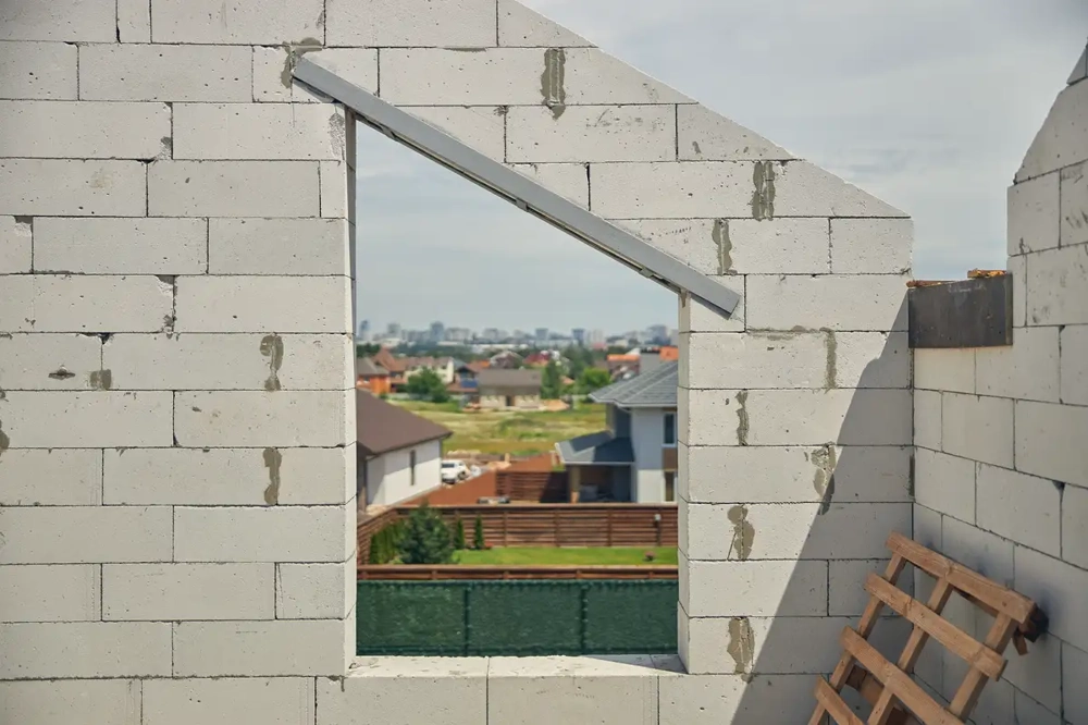 Ściany nośne z bloczków betonowych z otworem okiennym w trakcie budowy